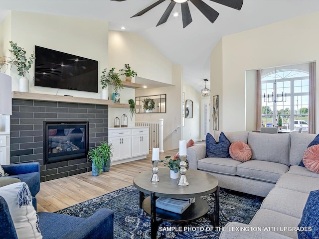 living area featuring a ceiling fan, light wood-style flooring, high vaulted ceiling, and a fireplace