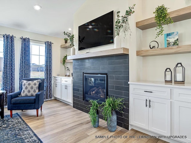 living room with light wood-style flooring, a tile fireplace, and recessed lighting