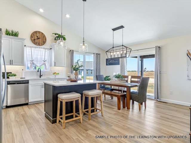 kitchen with stainless steel dishwasher, a center island, a chandelier, light wood finished floors, and light countertops
