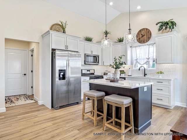 kitchen with stainless steel appliances, a sink, light countertops, a kitchen island, and tasteful backsplash