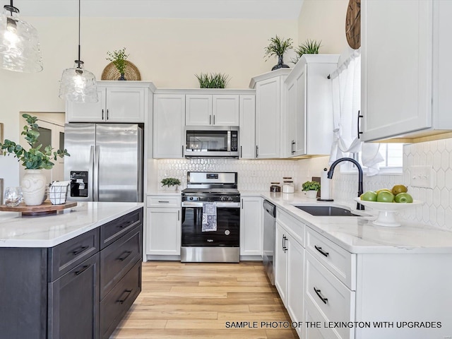 kitchen with appliances with stainless steel finishes, a sink, white cabinetry, and tasteful backsplash
