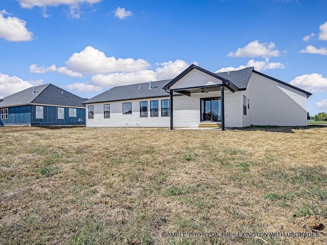 rear view of property featuring ceiling fan and a lawn