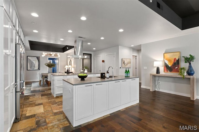 4545 Lindell Blvd Unit 3, Saint Louis, MO 63108 - kitchen with island range hood, an island with sink, baseboards, a chandelier, and white cabinetry