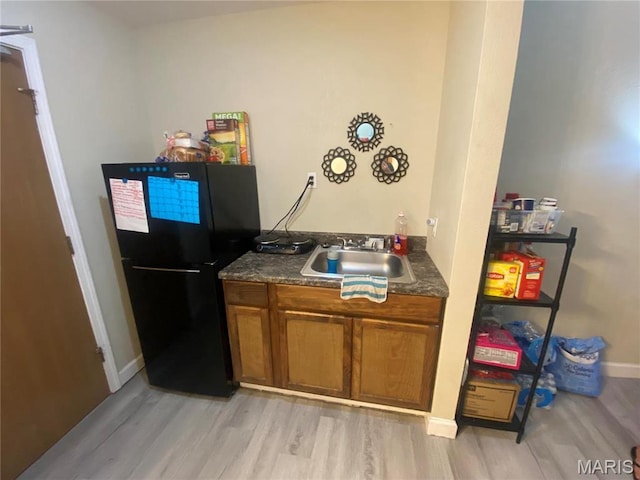 1 Proactive Dr, New Florence, MO 63363 - kitchen featuring freestanding refrigerator, a sink, light wood-style floors, brown cabinets, and baseboards