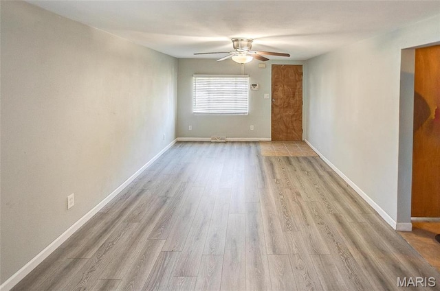 empty room with ceiling fan, wood finished floors, and baseboards
