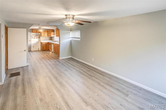 unfurnished living room with a ceiling fan, light wood-type flooring, and baseboards