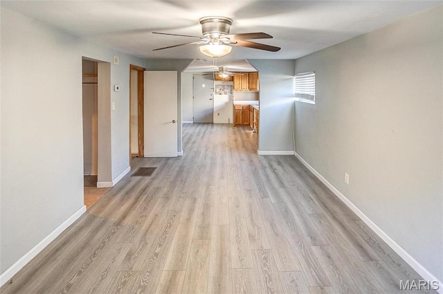spare room with ceiling fan, light wood-style flooring, and baseboards