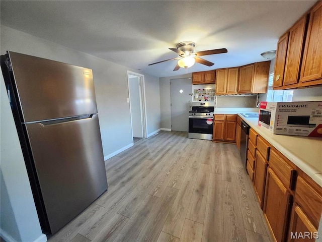 kitchen with appliances with stainless steel finishes, brown cabinetry, and light wood-type flooring
