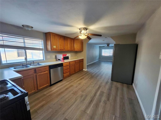 kitchen featuring dishwasher, a ceiling fan, electric range, a sink, and brown cabinetry