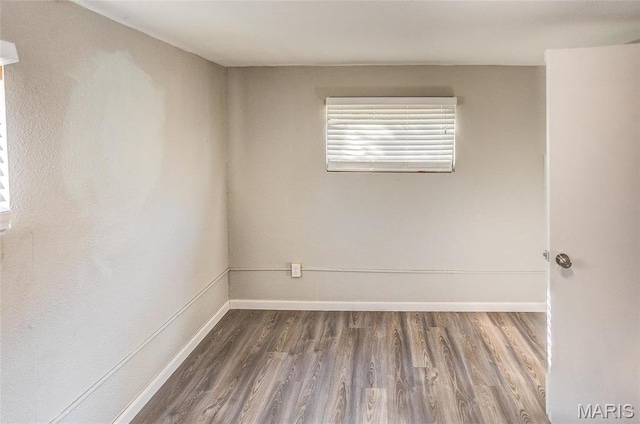 empty room featuring wood finished floors and baseboards