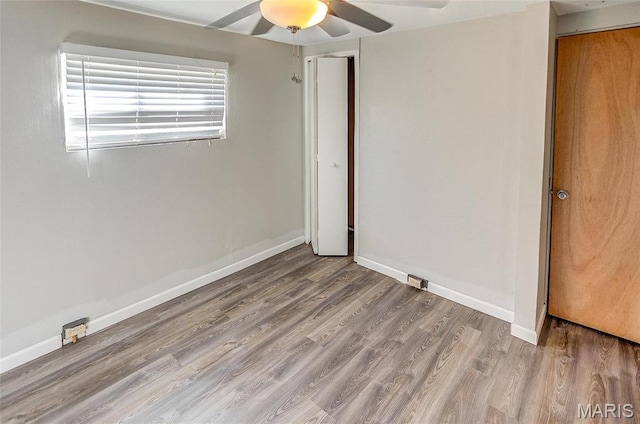 unfurnished bedroom with a closet, wood finished floors, a ceiling fan, and baseboards
