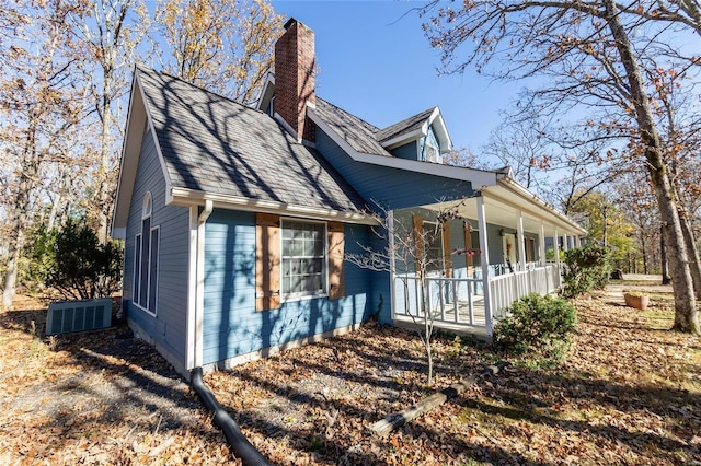 view of side of property with a porch, a chimney, and cooling unit