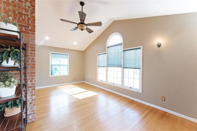 unfurnished living room featuring ceiling fan, plenty of natural light, vaulted ceiling, wood finished floors, and baseboards