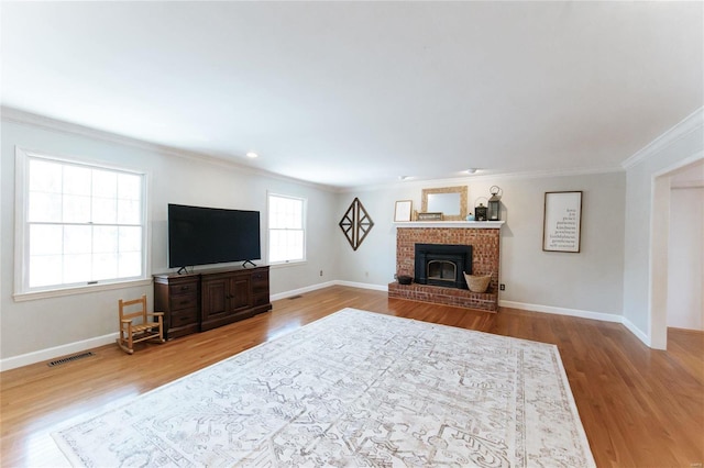 living area featuring crown molding, wood finished floors, baseboards, and a fireplace
