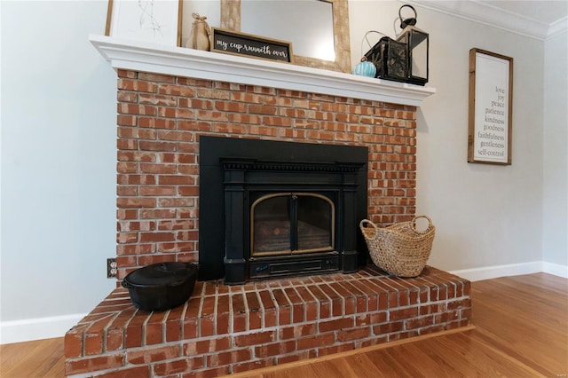 detailed view of baseboards, wood finished floors, ornamental molding, and a fireplace