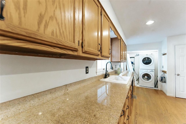 washroom featuring stacked washer / dryer, light wood-style flooring, and recessed lighting