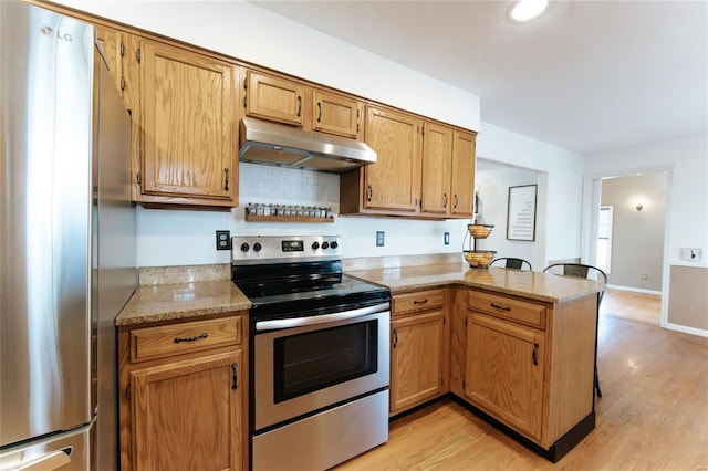 kitchen featuring appliances with stainless steel finishes, under cabinet range hood, a peninsula, and light wood-type flooring