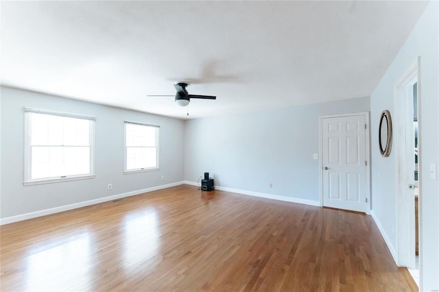 empty room with ceiling fan, wood finished floors, and baseboards