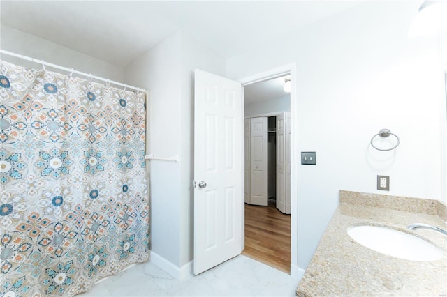 full bathroom with a sink, a shower with curtain, marble finish floors, and baseboards
