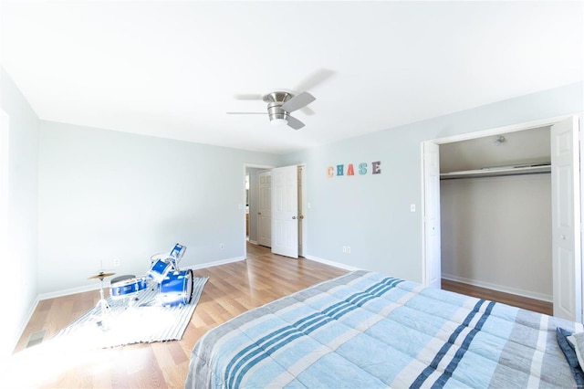bedroom featuring wood finished floors, baseboards, ceiling fan, and a closet