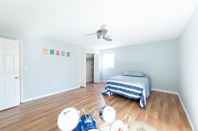 bedroom with wood finished floors, a ceiling fan, baseboards, and a closet