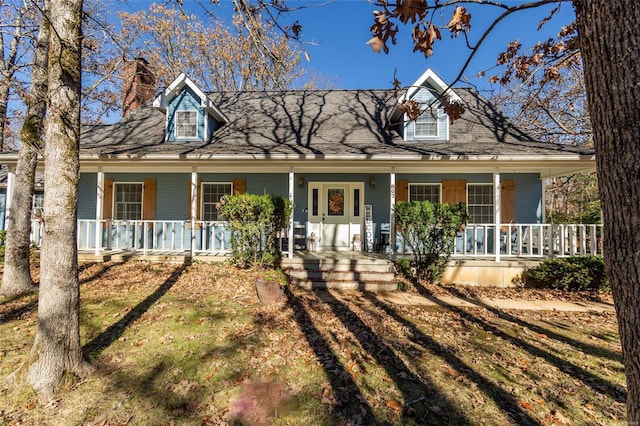 cape cod-style house featuring a porch and a chimney
