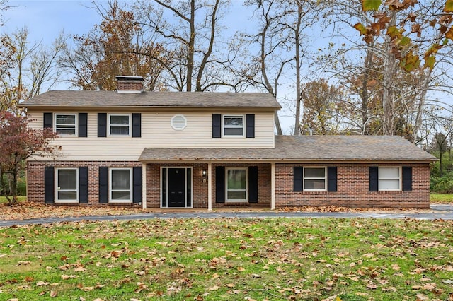 view of front of property with brick siding, a chimney, and a front yard