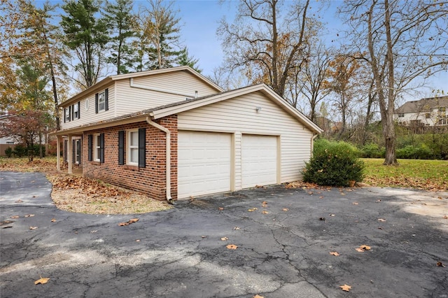 view of home's exterior featuring brick siding, an attached garage, and asphalt driveway