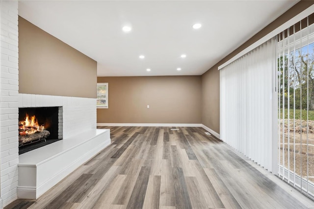 unfurnished living room featuring a fireplace, wood finished floors, recessed lighting, and baseboards