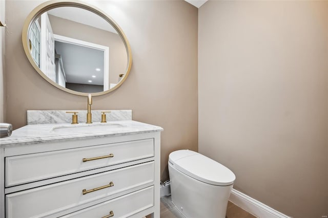 half bath featuring toilet, vanity, and baseboards
