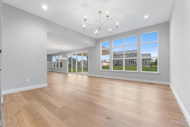 unfurnished living room with a chandelier, baseboards, light wood-type flooring, and recessed lighting