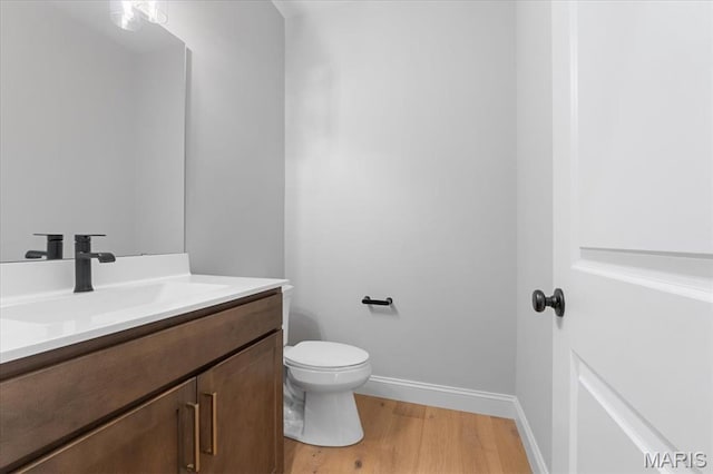 bathroom featuring wood finished floors, vanity, toilet, and baseboards