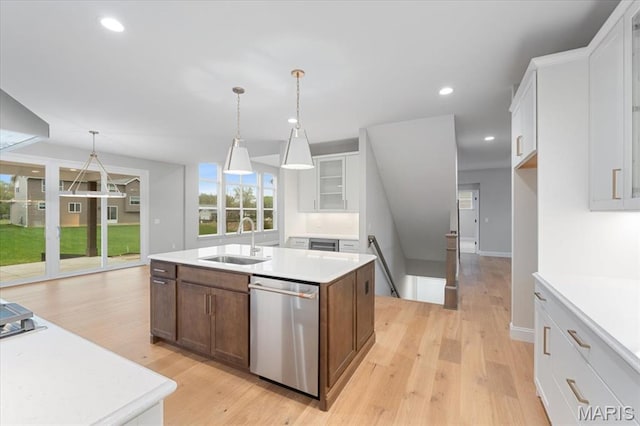 kitchen featuring dishwasher, a sink, light wood finished floors, light countertops, and white cabinetry