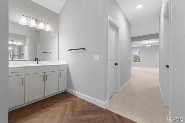 bathroom with baseboards, vanity, and recessed lighting
