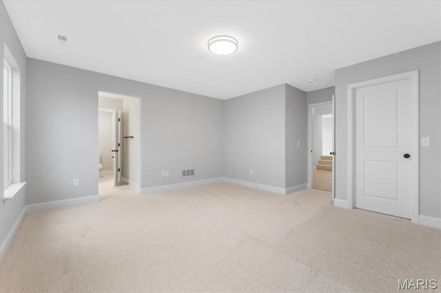 unfurnished bedroom with light carpet, baseboards, and connected bathroom