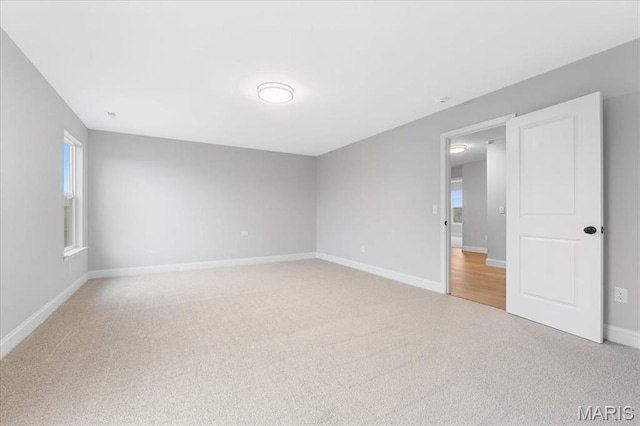 unfurnished room with light carpet and baseboards