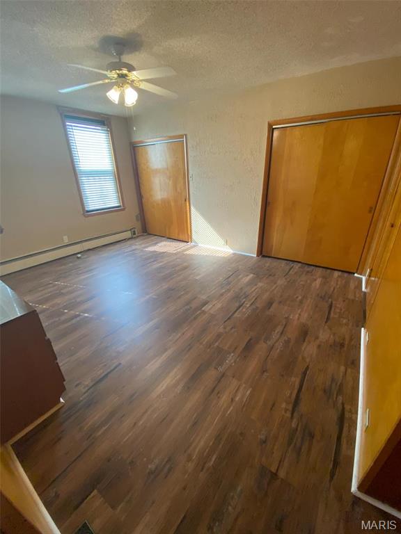 125 S 5th, Saint Charles, MO 63301 - unfurnished bedroom featuring a baseboard heating unit, wood finished floors, a textured ceiling, and ceiling fan