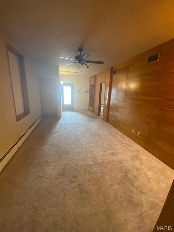 125 S 5th, Saint Charles, MO 63301 - carpeted spare room with a ceiling fan, a baseboard radiator, and wooden walls