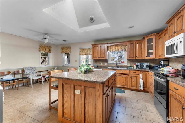 11 Schonhoff Cpe, Girardeau, MO 63703 - kitchen featuring electric range oven, white microwave, brown cabinetry, a center island, and tasteful backsplash