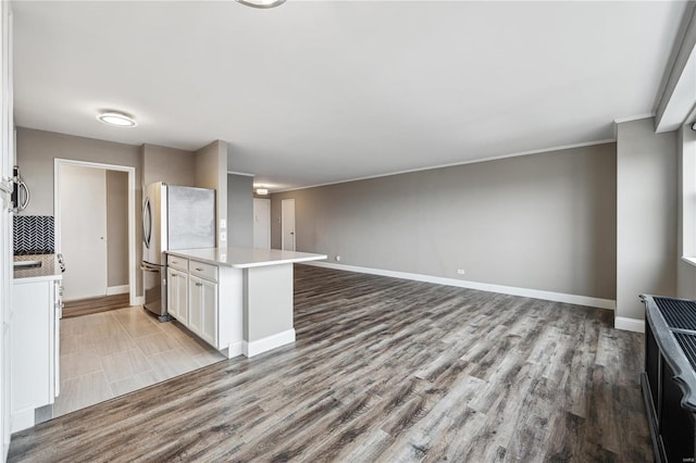 4466 W Pine Blvd Unit 22G, Saint Louis, MO 63108 - kitchen featuring freestanding refrigerator, wood finished floors, white cabinets, light countertops, and baseboards