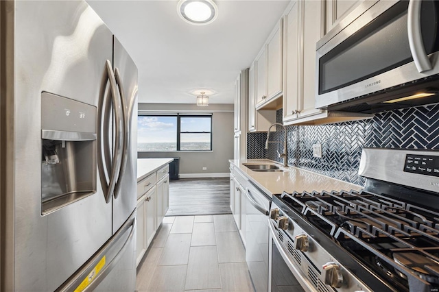 4466 W Pine Blvd Unit 22G, Saint Louis, MO 63108 - kitchen with stainless steel appliances, a sink, decorative backsplash, baseboards, and light countertops