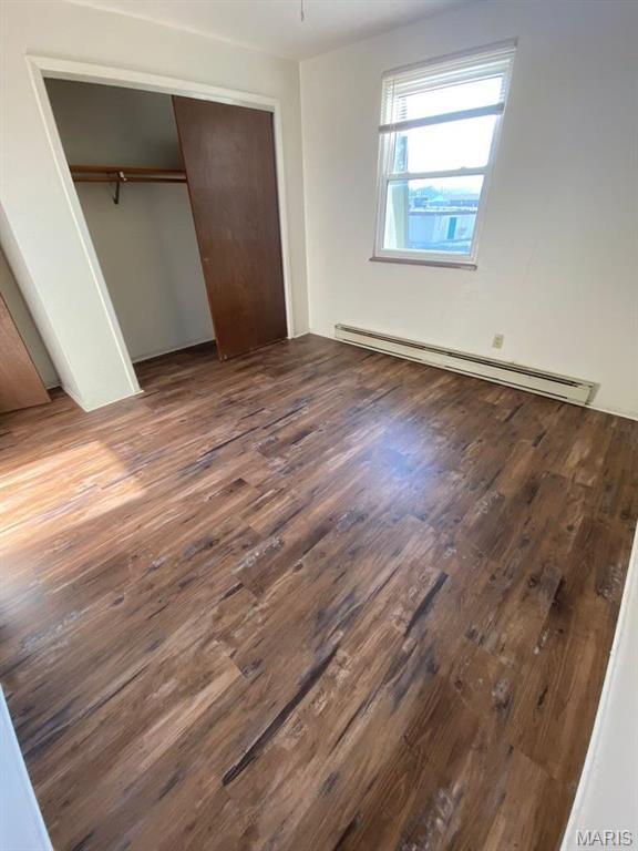 753 Rozier St, Saint Genevieve, MO 63670 - unfurnished bedroom with a baseboard heating unit, dark wood-style floors, and a closet