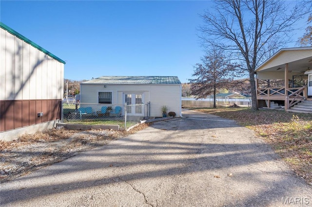 9136 Beach Dr, French Village, MO 63036 - view of side of home featuring french doors, driveway, fence, and metal roof