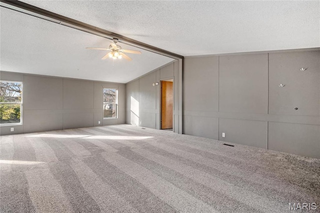 unfurnished room with a decorative wall, a textured ceiling, carpet floors, and ceiling fan