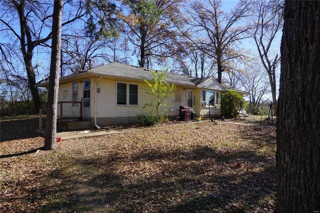 back of house featuring roof with shingles