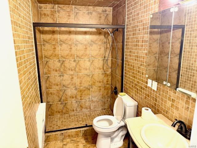 full bath featuring a shower stall, tile walls, toilet, and vanity