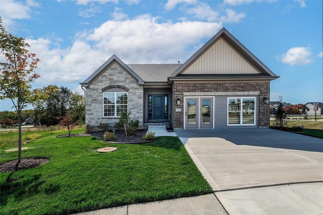 view of front of house with board and batten siding, a front lawn, brick siding, and stone siding