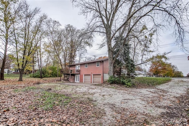 23388 Glenda Ave, Jerseyville, IL 62052 - rear view of house featuring an attached garage, a wooden deck, and dirt driveway