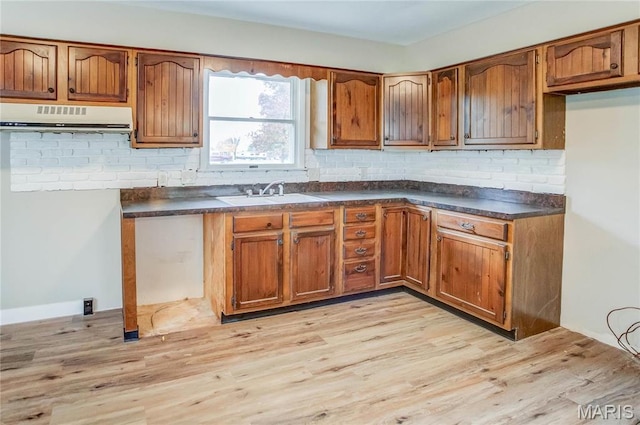 23388 Glenda Ave, Jerseyville, IL 62052 - kitchen featuring ventilation hood, brown cabinets, dark countertops, backsplash, and light wood-type flooring
