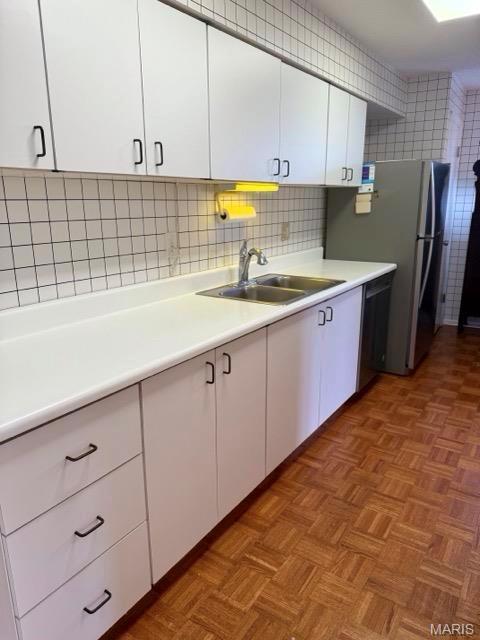 10367 Oxford Hill Dr Unit 26, Saint Louis, MO 63146 - kitchen featuring a sink, white cabinets, light countertops, dishwasher, and tasteful backsplash